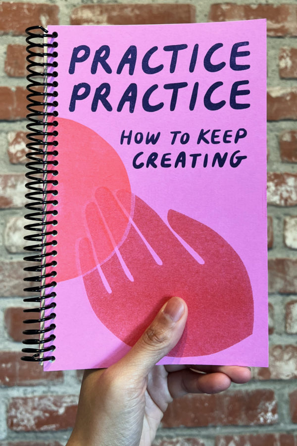 Victoria Silva's hand holds a spiral-bound book in front of a brick wall. The cover reads, "Practice Practice: How to Keep Creating"